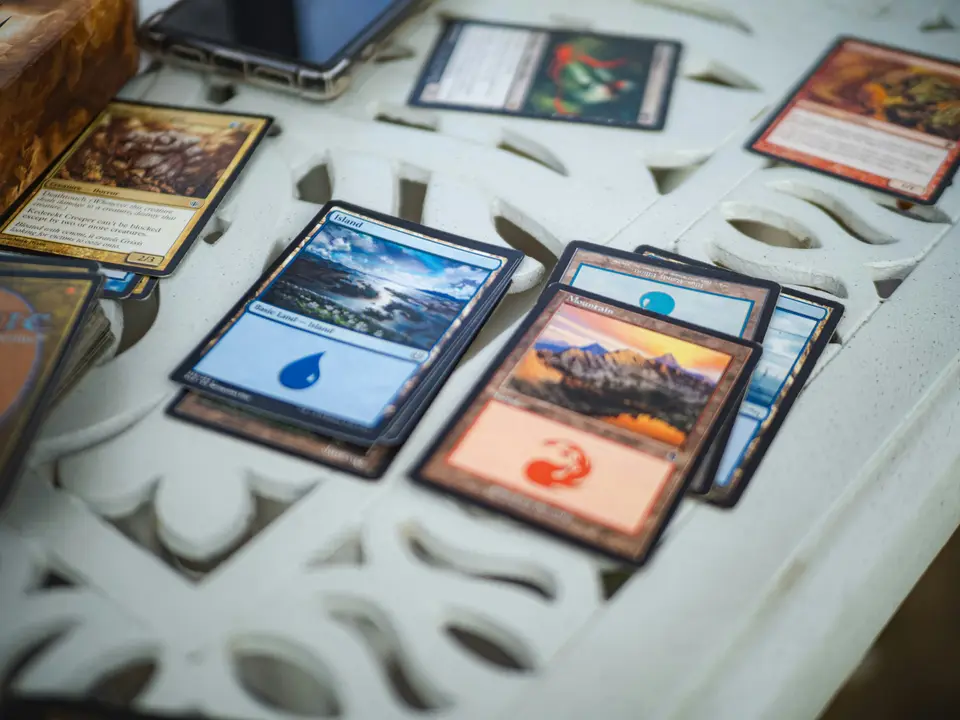 Magic-Spielkarten mit blauen und roten Landkarten liegen auf einem weißen Gittertisch.